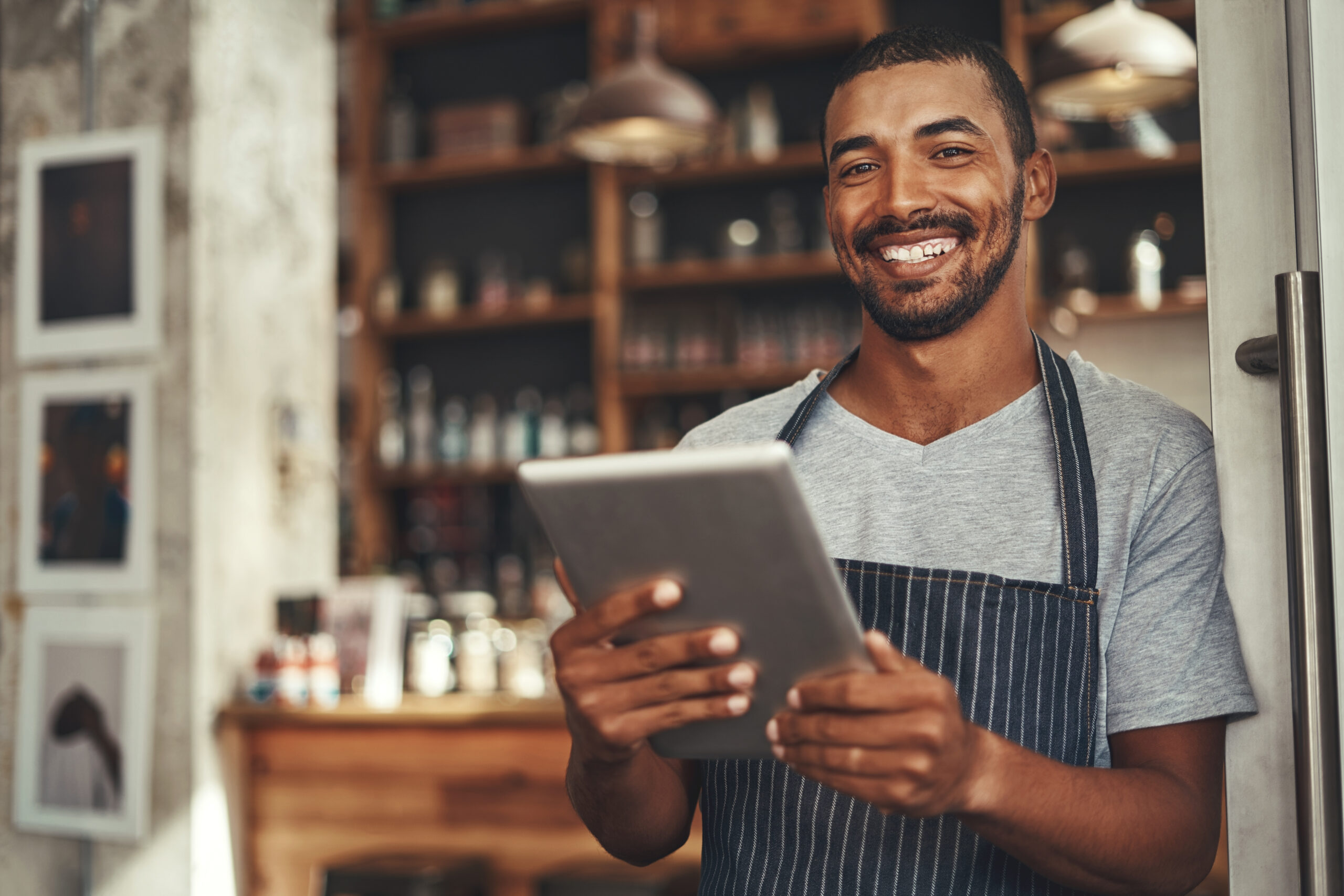 Smiling male cafe owner holding digital tablet in his hand